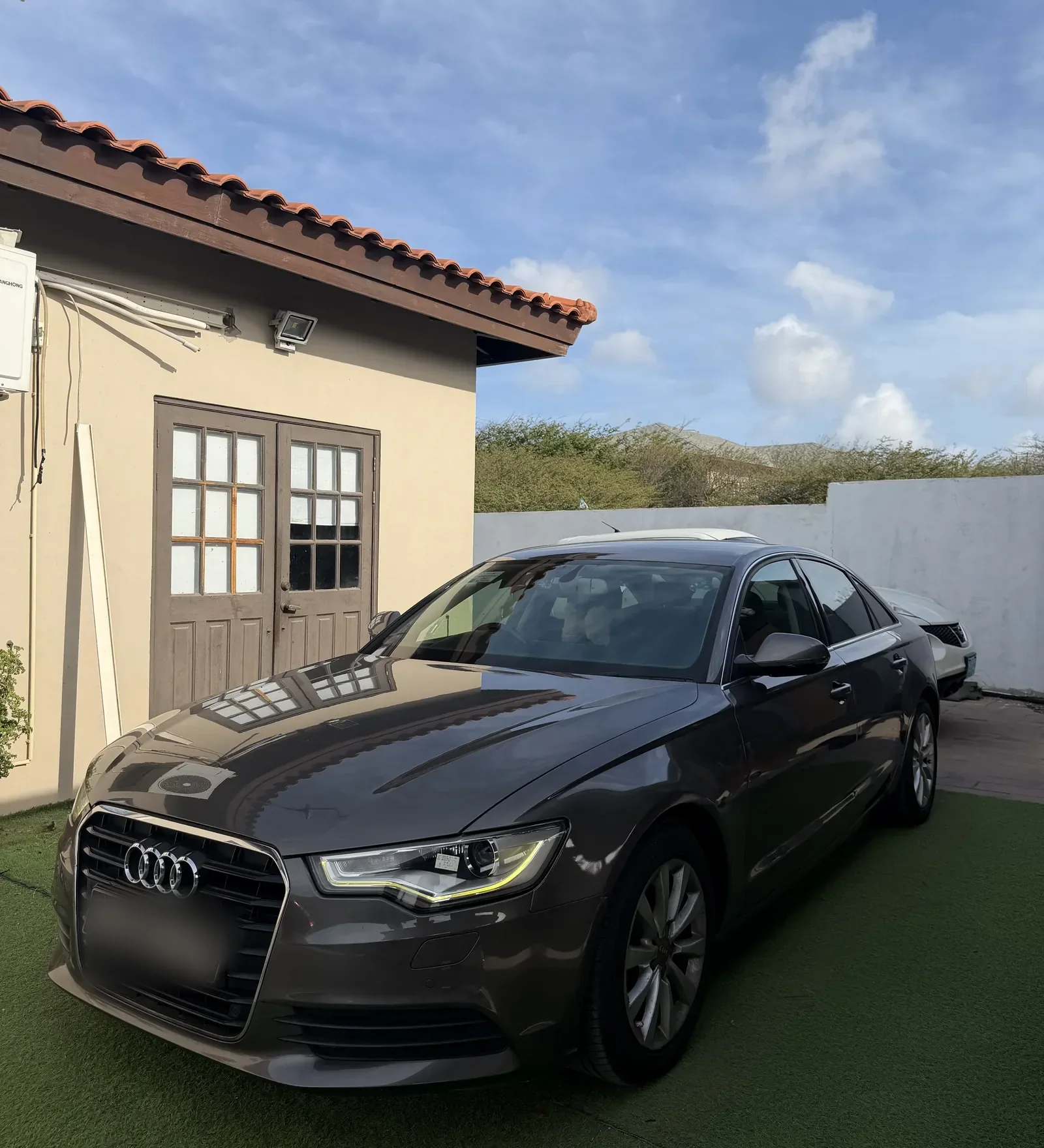 An Audi A6 with tinted windows parked in Aruban daylight
