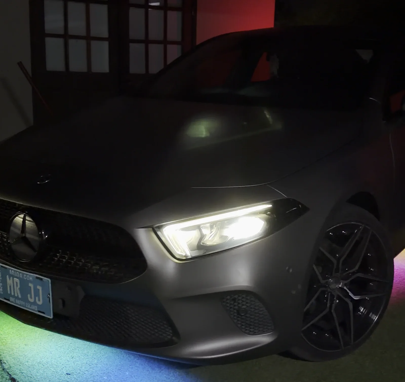 Underglow cycling through green and blue under a Mercedes CLA at night
